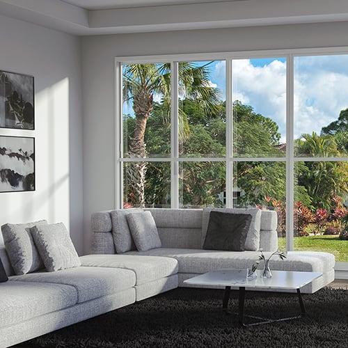A three season room addition inside room view with gray couches, a white coffee table, and large windows